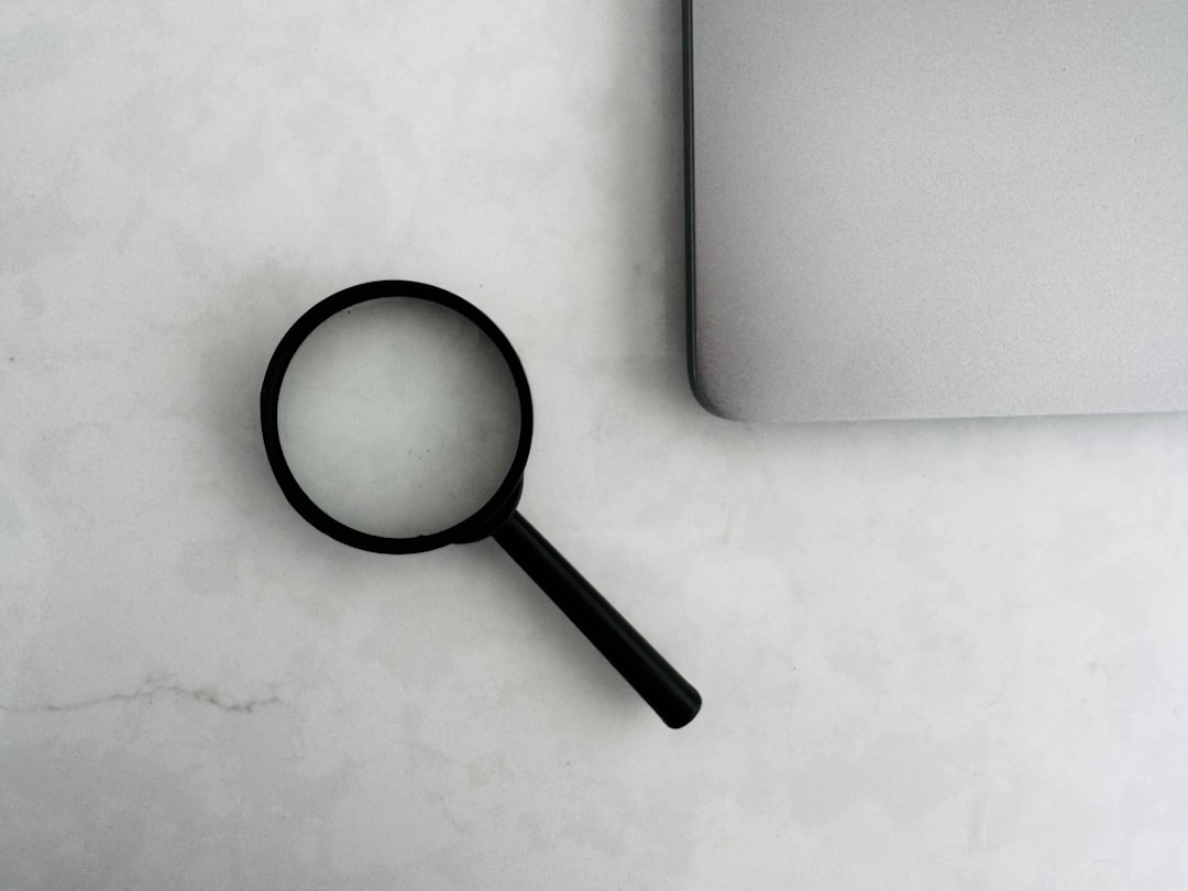 A magnifying glass beside a laptop on a table