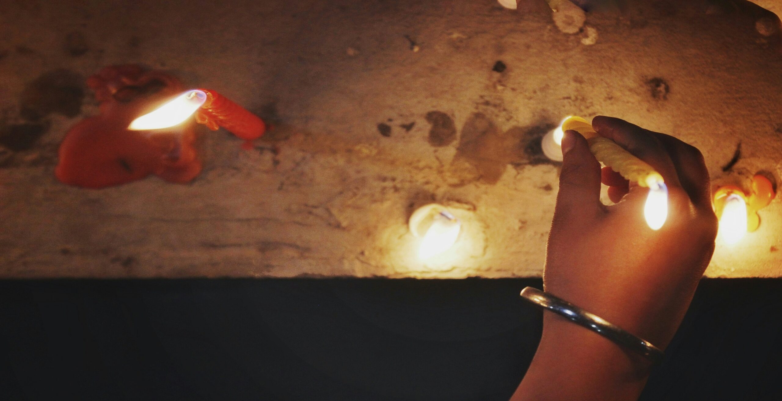 A hand holding a lit candle