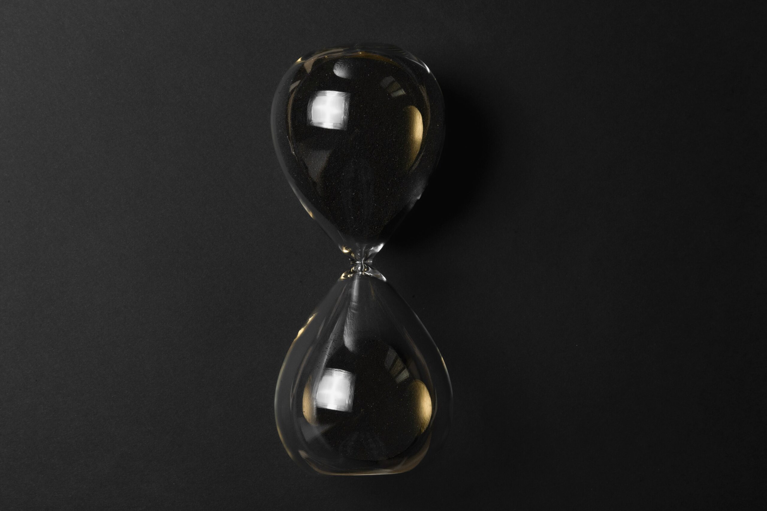 Clear glass hour glass on black surface