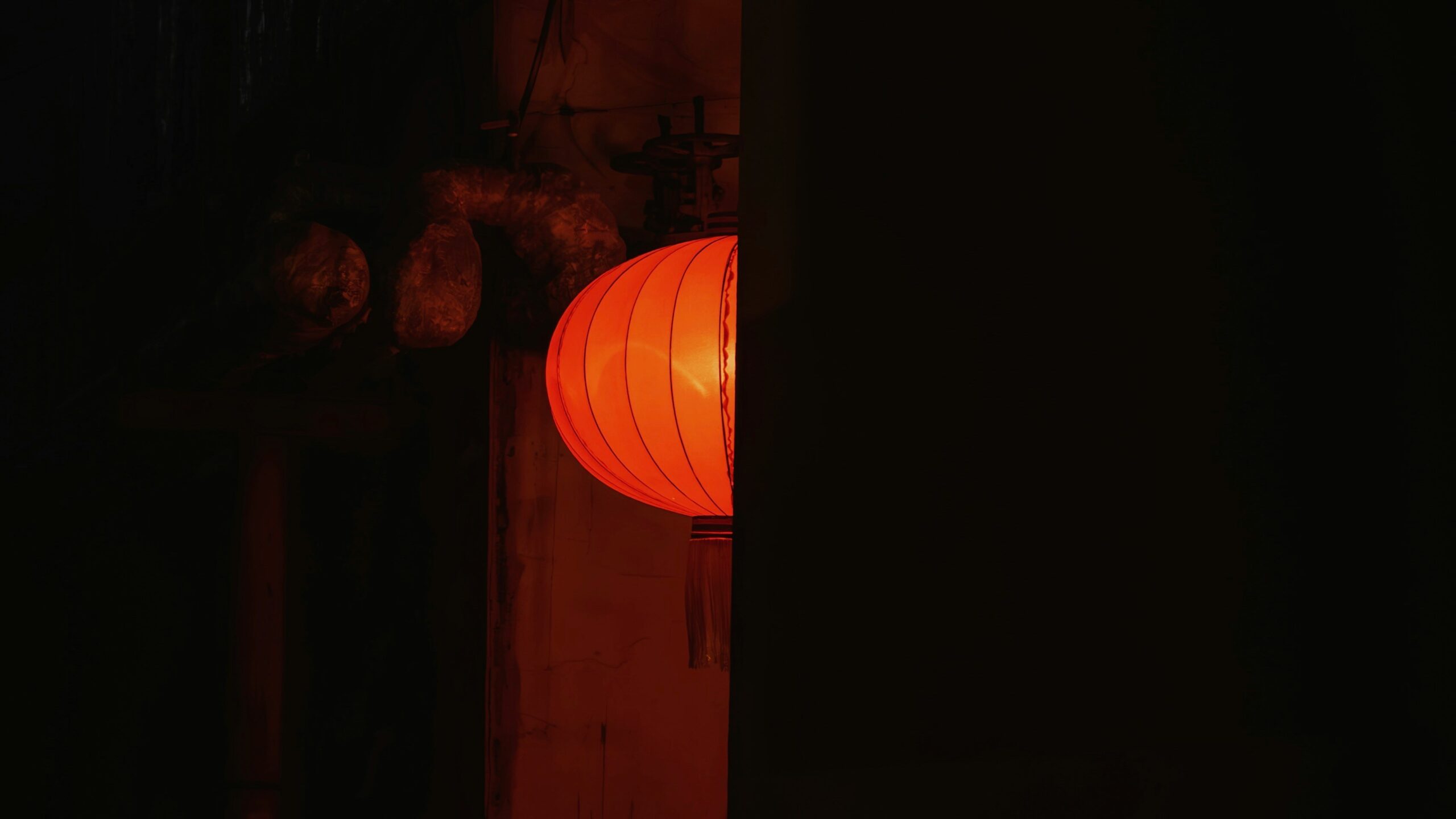 A glowing orange lantern peeks from darkness