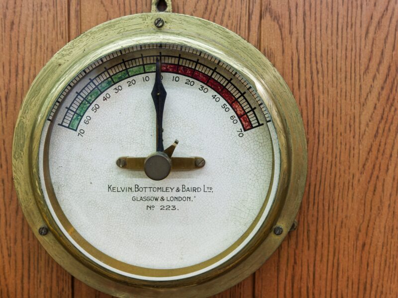 A close up of a thermometer on a wooden wall