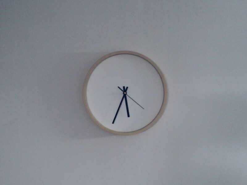 A simple clock hangs on a white wall.
