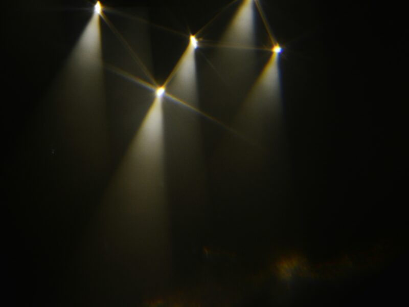 Stage lights illuminating a dark space with haze.